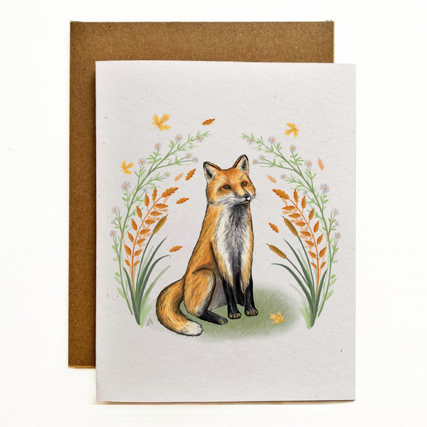 Recycled card stock greeting card with an illustration of a hand drawn fox sitting on his hind legs with front paws stretched in front. He is surrounded by yellow and orange autumn leaves and foliage.