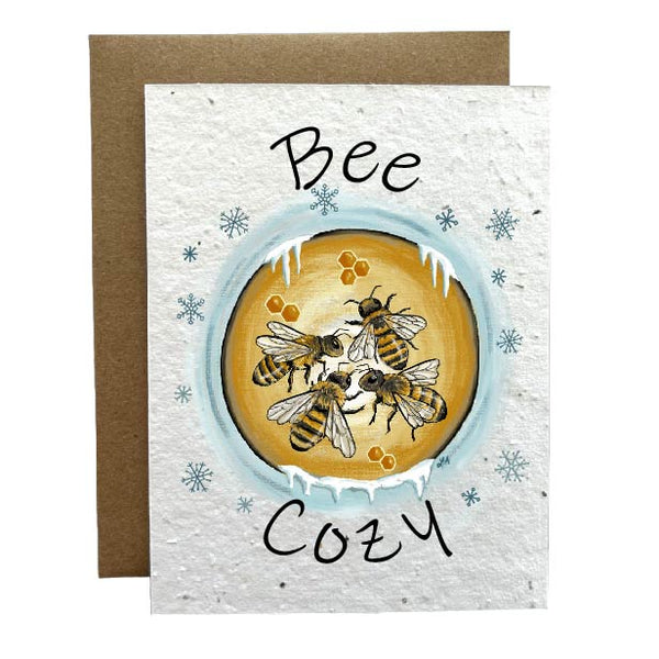 Plantable greeting card featuring a cozy winter-themed design of bees nestled in their hive to stay warm, with the text 'Bee Cozy.' Made from seed paper that grows wildflowers when planted.